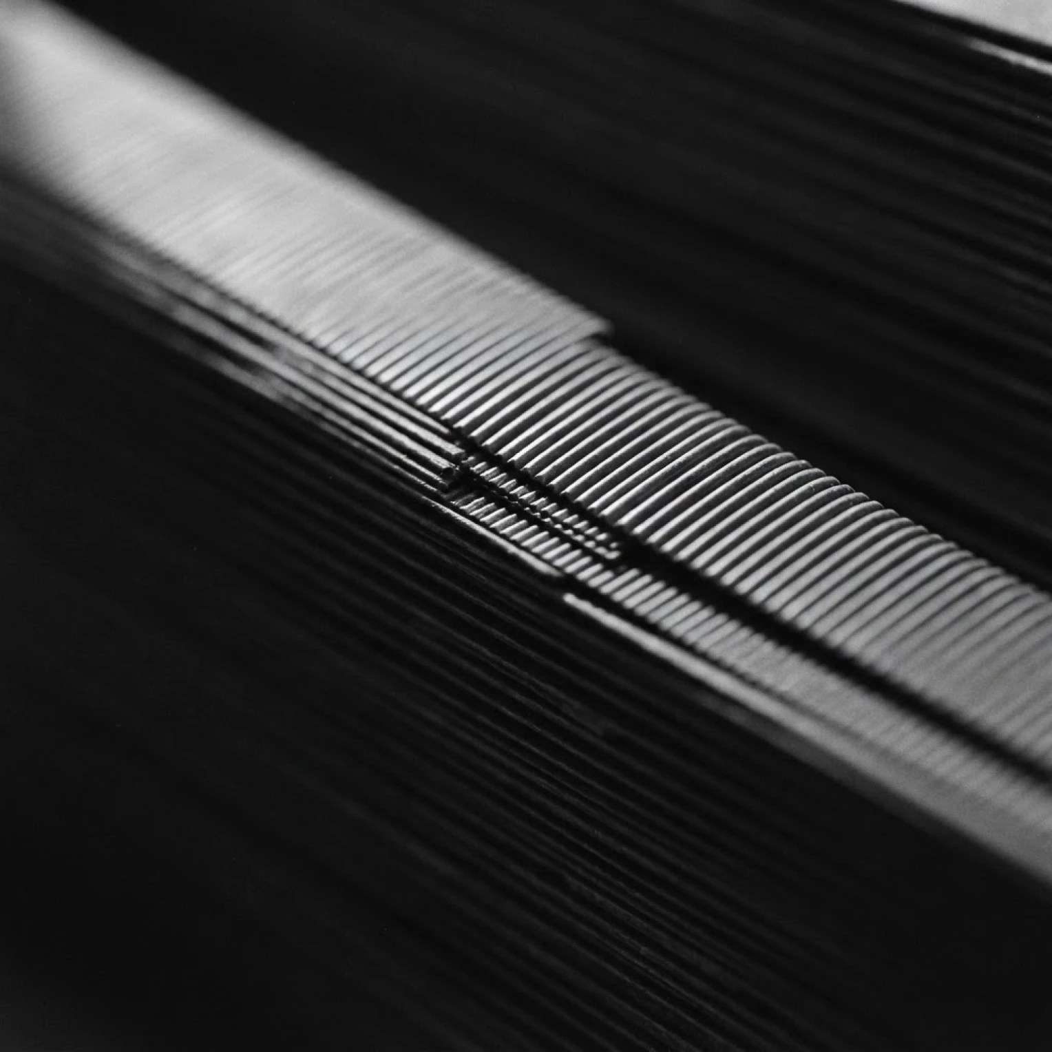 A diagonal ridge of tightly stacked fine lines, lit along its edge against black